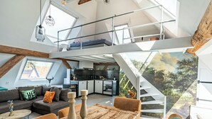 Un espace de vie de style loft comprenant une cuisine, un coin repas et un escalier menant à un niveau supérieur.