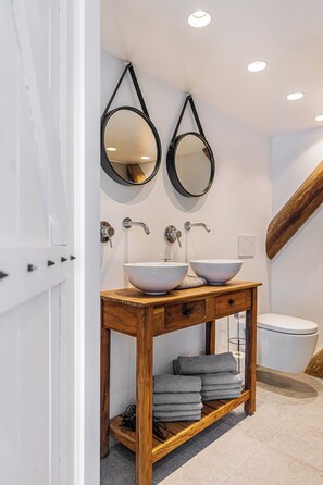 Une salle de bain avec deux lavabos, un meuble-lavabo en bois et deux miroirs fixés au mur.
