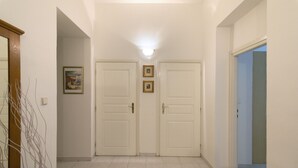 Ein Flur mit zwei weißen Türen, einer Deckenleuchte und einem gerahmten Bild an der Wand.
