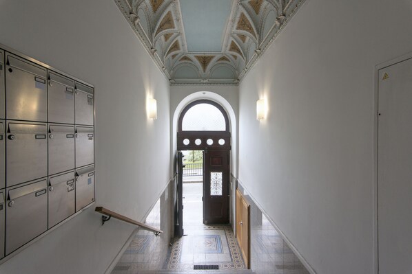 A hallway with lockers, a wooden handrail, and a patterned floor.