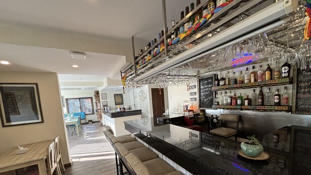 A modern bar area with a long counter, multiple stools, and a variety of bottles and glasses. - ViaVia boutique hotel - Kathmandu (Kathmandu)