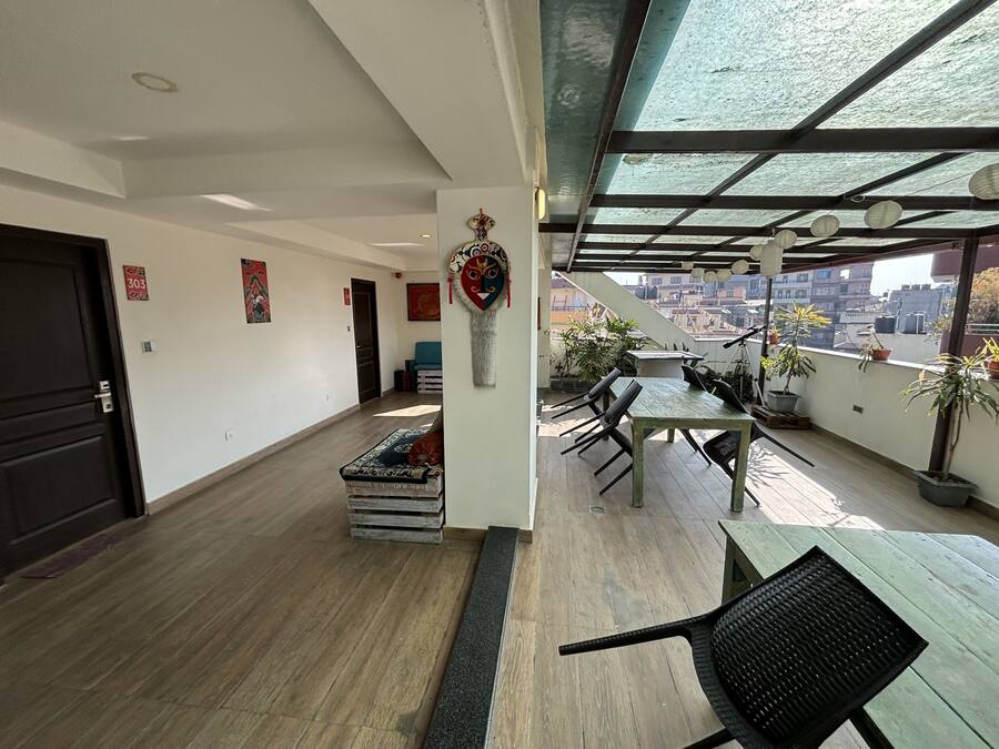 Amplia habitación con suelo de madera, una mesa de comedor con sillas, un sofá y un amplio ventanal con vistas a edificios.