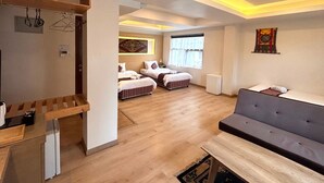 A spacious room with a wooden floor, a sofa, a bed with striped bedding, and a small table. - ViaVia boutique hotel - Kathmandu (Kathmandu)
