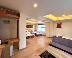 Um quarto espaçoso com piso de madeira, um sofá, uma cama com roupa de cama listrada e uma pequena mesa.