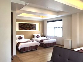Una habitación de hotel con dos camas, un ventanal grande y una lámpara en el techo.