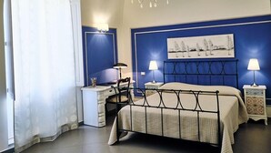 Un dormitorio con cama, mesitas de noche, un escritorio y una silla.