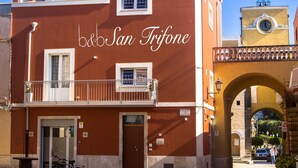 Un edificio rojo con balcones y un letrero que dice "b&b San Trifone".