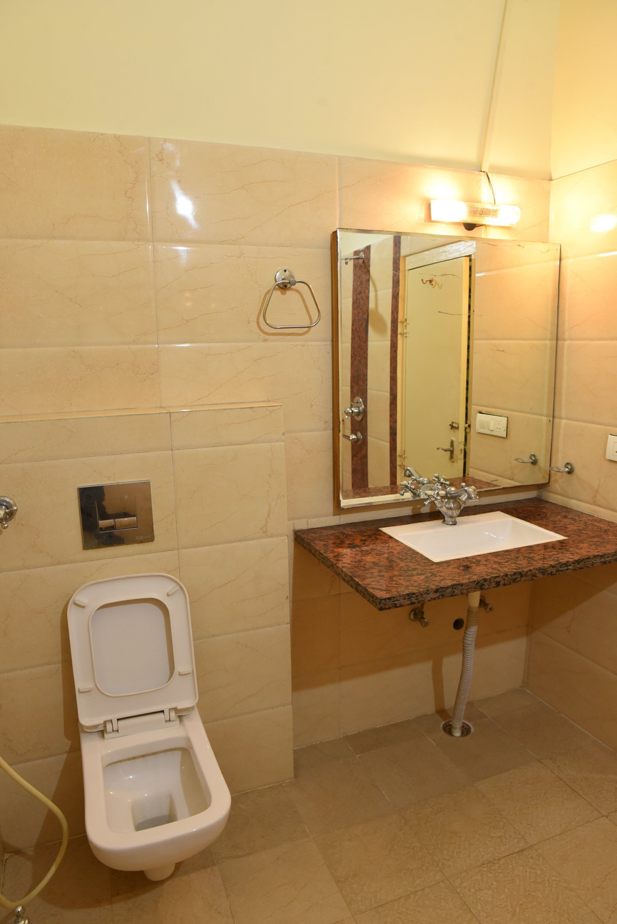 Un baño con inodoro, lavabo, espejo y apliques de pared.