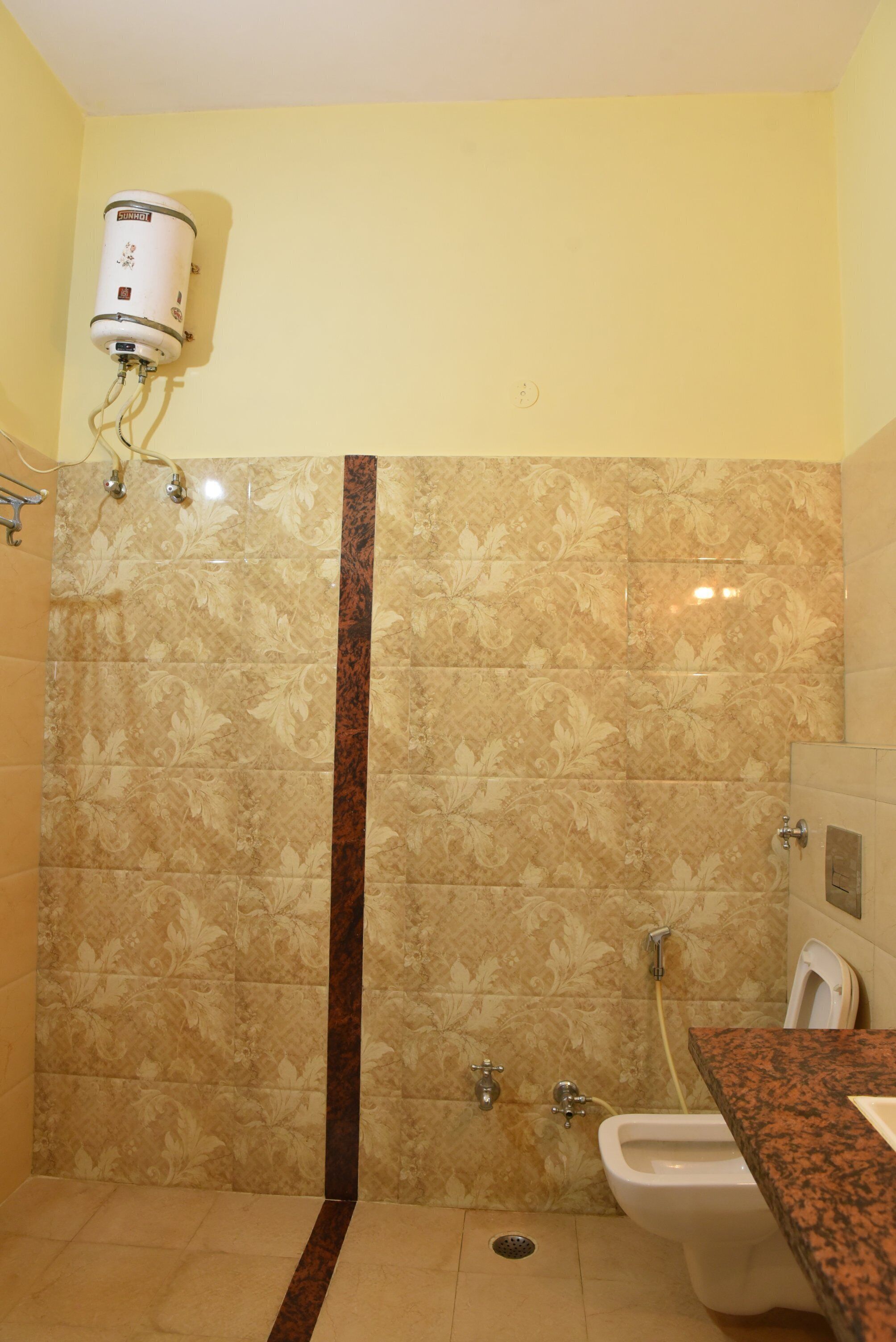 A bathroom with a shower, toilet, and a water heater mounted on the wall.
