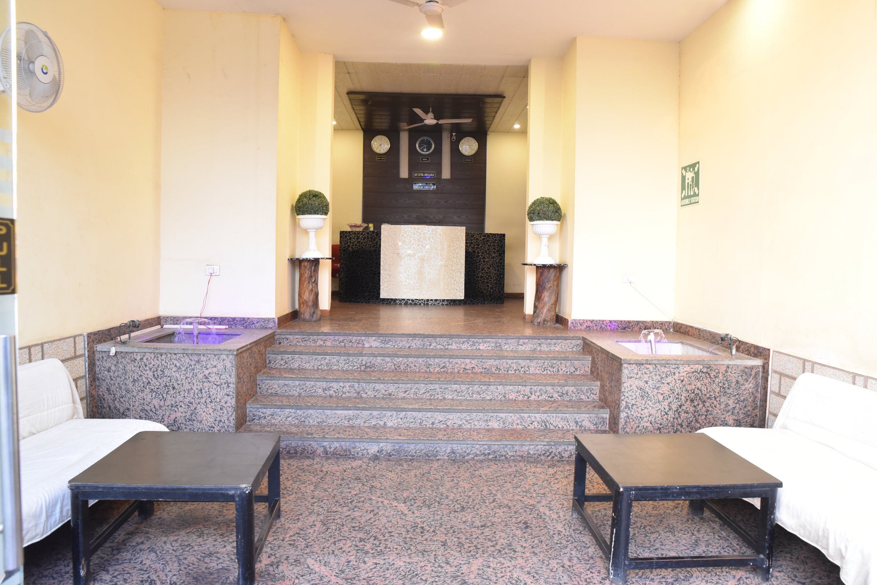 Un área de recepción con un mostrador, dos sofás, una pequeña mesa y una escalera que lleva al segundo piso.