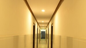 Um corredor comprido e estreito, com piso de mármore e paredes em tons claros.