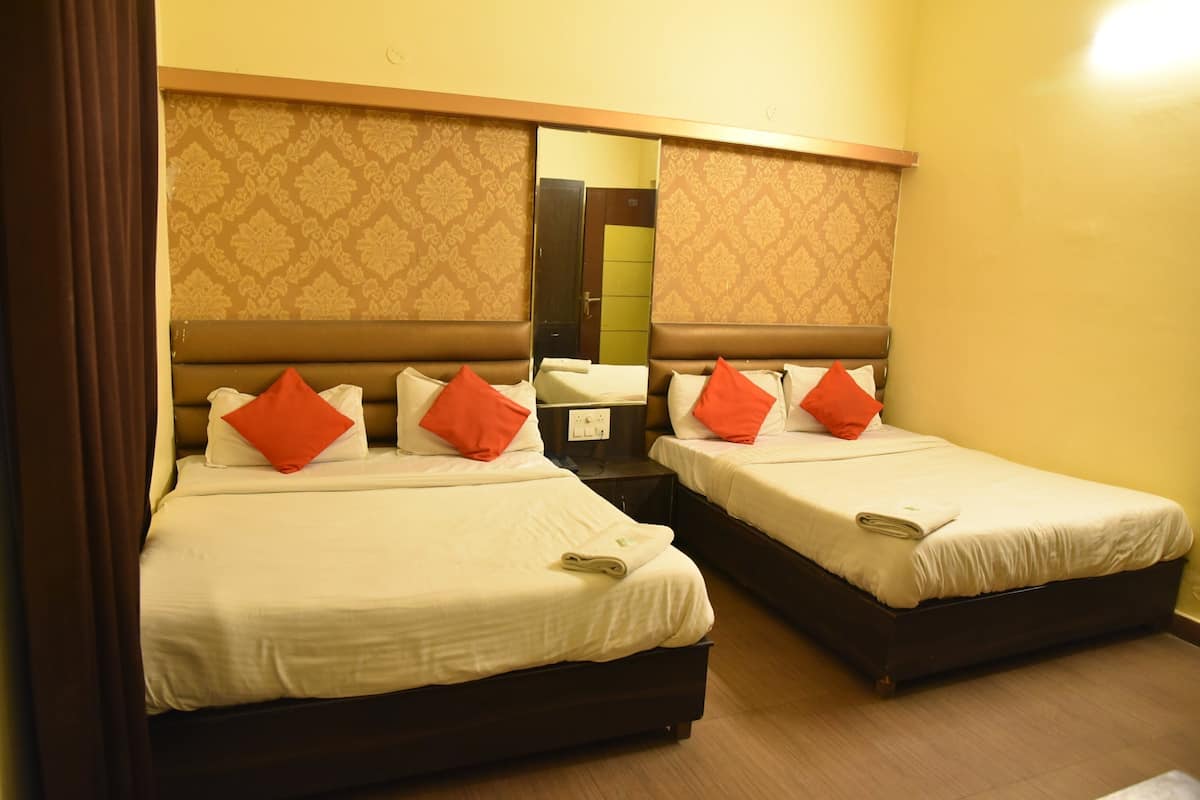 A hotel room with two beds, each with white bedding and orange pillows, a mirror above the beds, and a patterned wall.