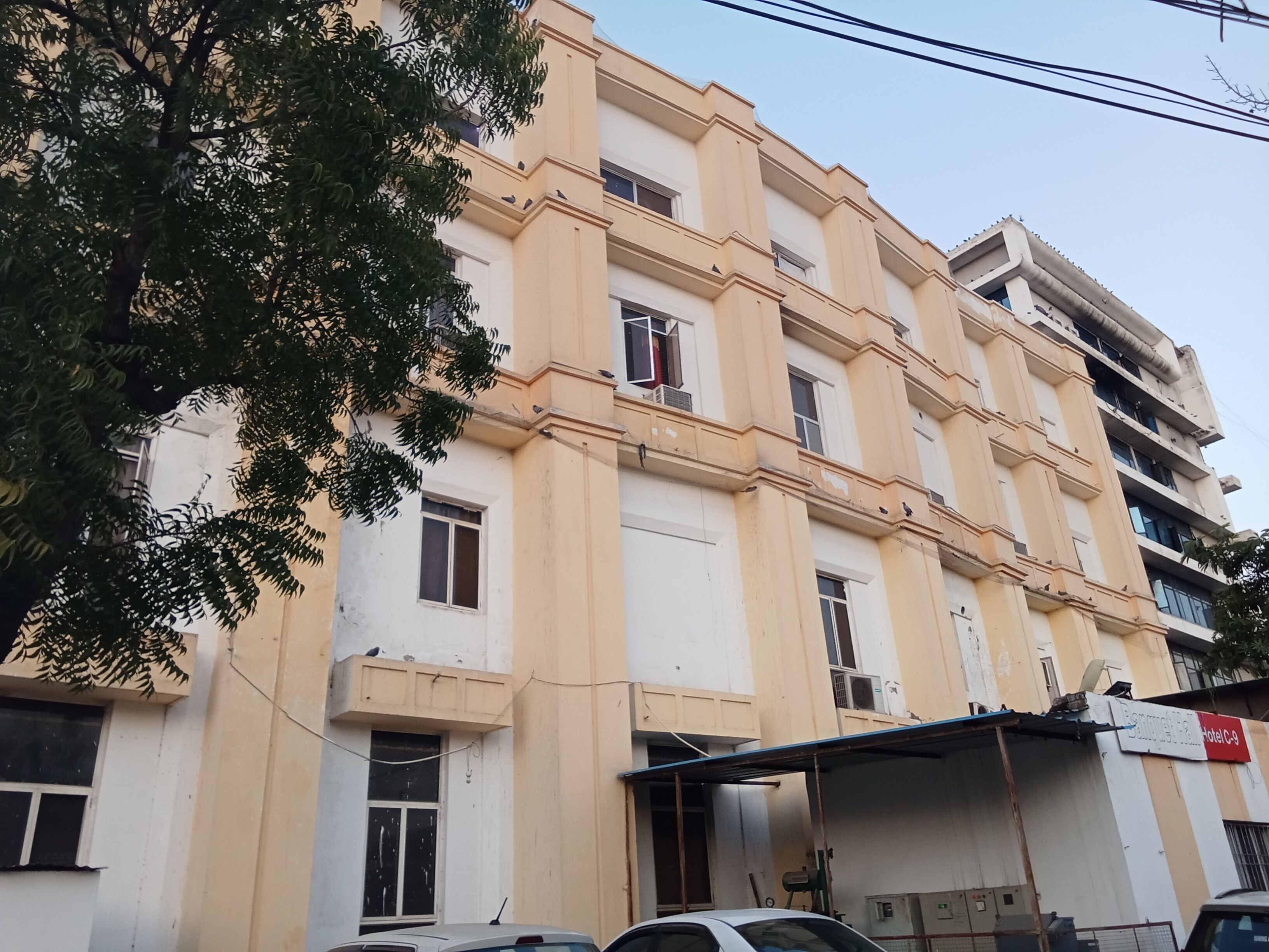 Un immeuble à plusieurs étages, doté d’une façade beige, de nombreuses fenêtres et d’une entrée bien visible.
