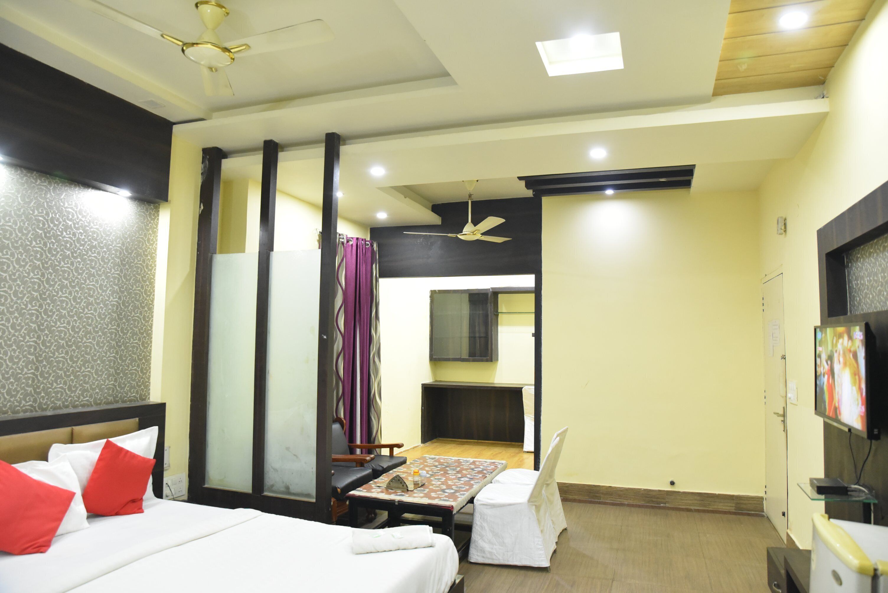 A hotel room with a bed, a desk, a chair, a TV, and a ceiling fan.