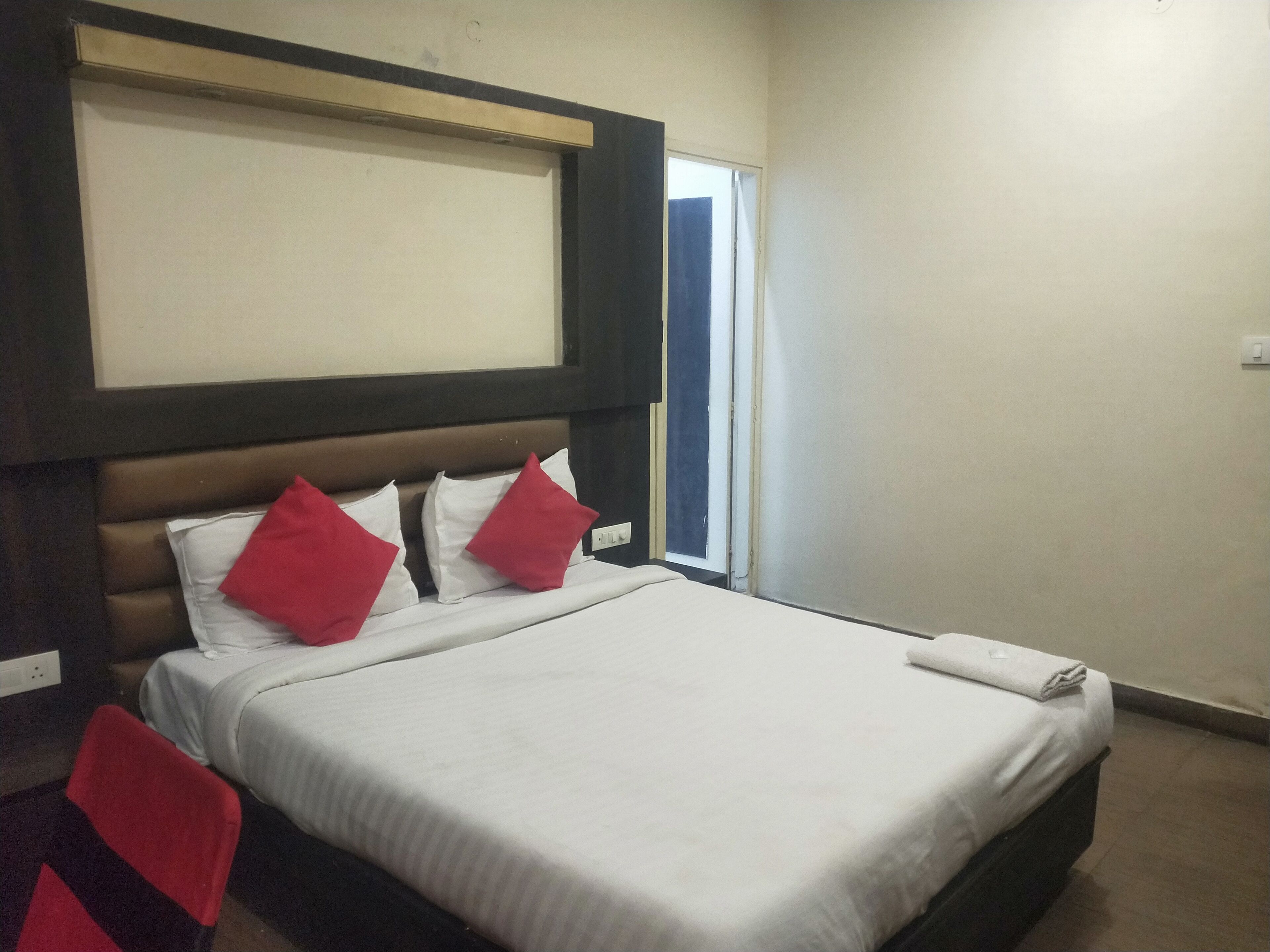 Ein Hotelzimmer mit Bett, Fenster und einem an der Wand befestigten Fernseher.