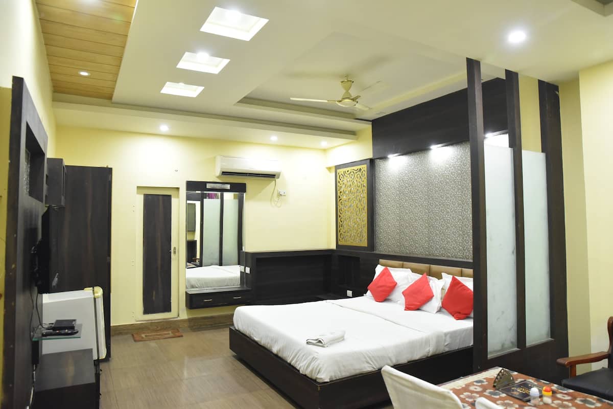 A hotel room with a bed, a desk, a chair, a ceiling fan, and an air conditioning unit.