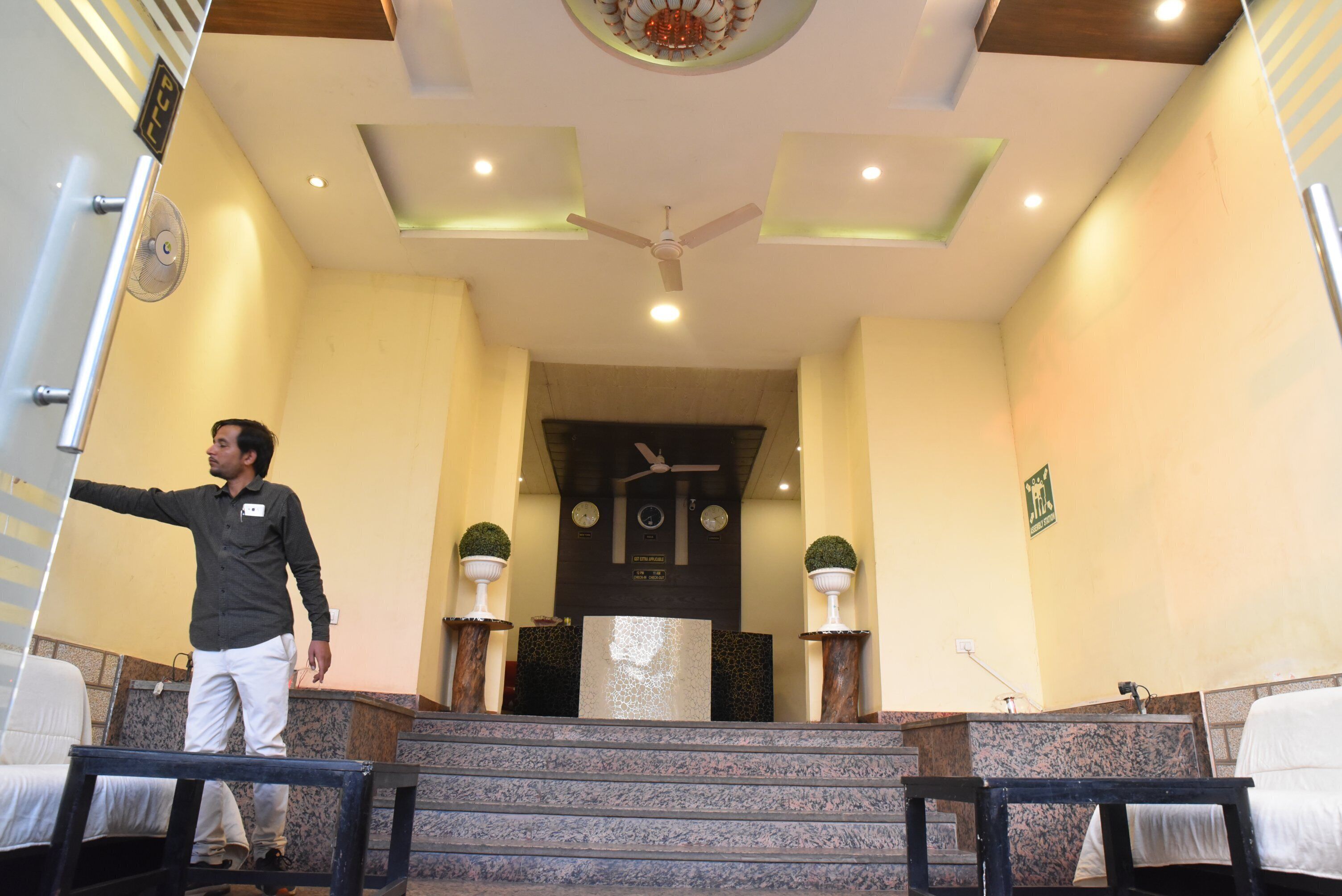 Um saguão de hotel com balcão de recepção, escada e ventilador de teto.