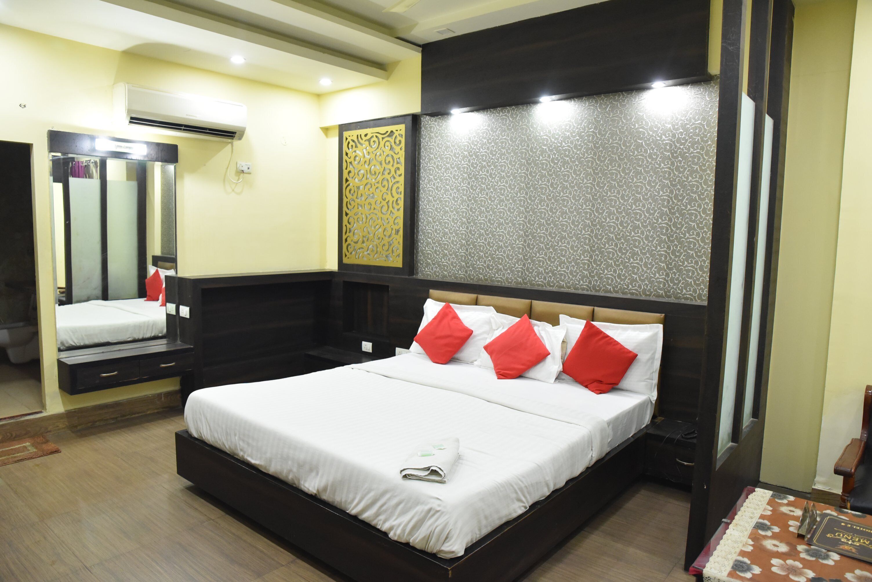 Una habitación de hotel moderna con una cama grande, un espejo, un armario y un equipo de aire acondicionado.