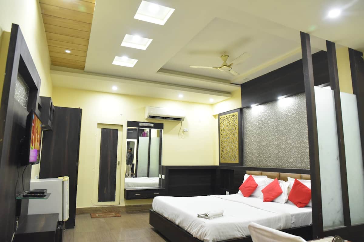 A hotel room with a bed, a ceiling fan, recessed lighting, a mirror, and a television.