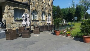 A stone building with outdoor seating and potted plants. - Landhotel Wettin (Hermsdorf-Erzgebirge)