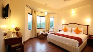 A hotel room with a bed, bedside table, lamp, and a view of the outdoors. - Hotel Germanus (Madurai)