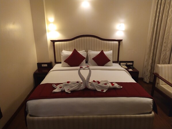 A hotel room with a neatly made bed, a bedside table with a lamp, and a chair.