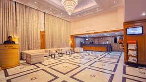 A hotel reception area with a reception desk, seating area, and a chandelier. - Hotel Germanus (Madurai)