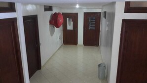 Un pasillo con puertas de madera, suelo de baldosas y un bolso rojo colgado en la pared.