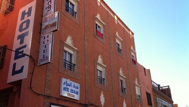 Un hotel con varios letreros, incluyendo un letrero grande que dice "HOTEL" y otro que indica "HOTEL ES SALAM".