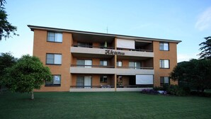 A multi-story building with balconies, a sign reading "Akuna," and a well-maintained lawn in front. - Akuna 8 (Forster)