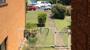 A residential area with a brick house, a fenced yard, and parked cars. - Akuna 8 (Forster)