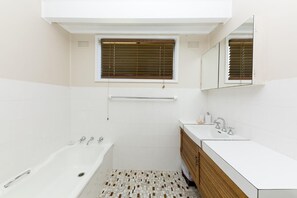 A modern bathroom with a bathtub, a sink, and a vanity. - Beach Cottage (Forster)