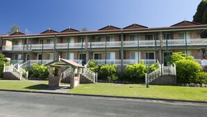 A two-story brick building with a red-tiled roof, multiple balconies, and a well-maintained lawn. - Birchgrove Terrace Unit 6 (Tuncurry)