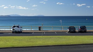 A parking lot with vehicles parked along a beachfront. - Ebbtide Unit 04 (Forster)