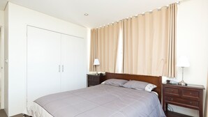 A bedroom with a bed, bedside tables, a wardrobe, and curtains. - Ebbtide Unit 04 (Forster)