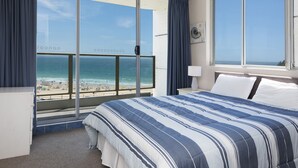 A hotel room with a large window offering a view of the beach and ocean. - Ebbtide Unit 17 (Forster)
