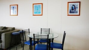 En matplats med ett runt bord i glas, blå stolar och inramade konstverk på väggen.