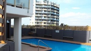 A swimming pool with a metal ladder, surrounded by a tiled deck. - Ebbtide Unit 33 (Forster)