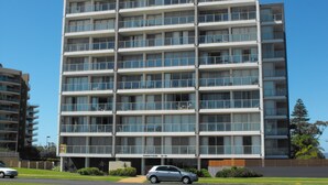 A multi-story building with a modern architectural design, featuring a series of balconies and large windows. - Ebbtide Unit 33 (Forster)