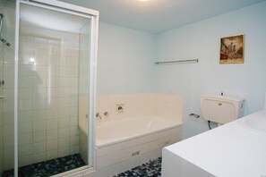 A bathroom with a glass shower enclosure, a bathtub, and a toilet. - Ebbtide Unit 33 (Forster)