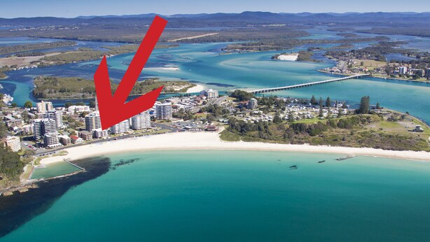 Vista aérea de un resort costero con playa, un puente y un puerto deportivo.