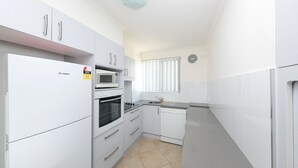 Una cocina moderna con armarios blancos, horno integrado, microondas y lavavajillas.
