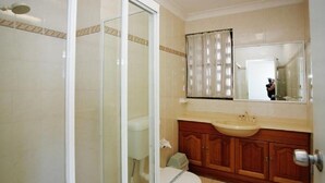 A bathroom with a toilet, sink, and wooden cabinets. - El Sandi Unit 10 (Forster)