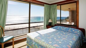 A room with a bed, a chair, a window with a view of the beach, and a lamp. - El Sandi Unit 10 (Forster)
