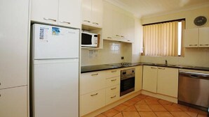 A kitchen with white cabinets, a microwave, an oven, and a dishwasher. - El Sandi Unit 10 (Forster)