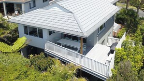 Une maison à deux étages dotée d’un balcon et d’un patio couvert.
