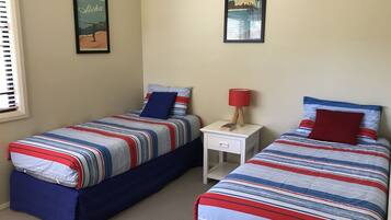 A bedroom with two beds, each with striped bedding and pillows, a nightstand with a lamp, and framed pictures on the wall.