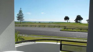 A balcony with a view of a road and grassy area. - Hi Surf Unit 2 (Forster)