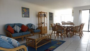 A living room with a sofa, chairs, a coffee table, and a bookshelf. - Hi Surf Unit 4 (Forster)