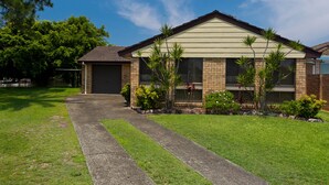 A two-story house with a brick facade, a garage, and a well-maintained lawn. - Lake House on Elouera (Forster)